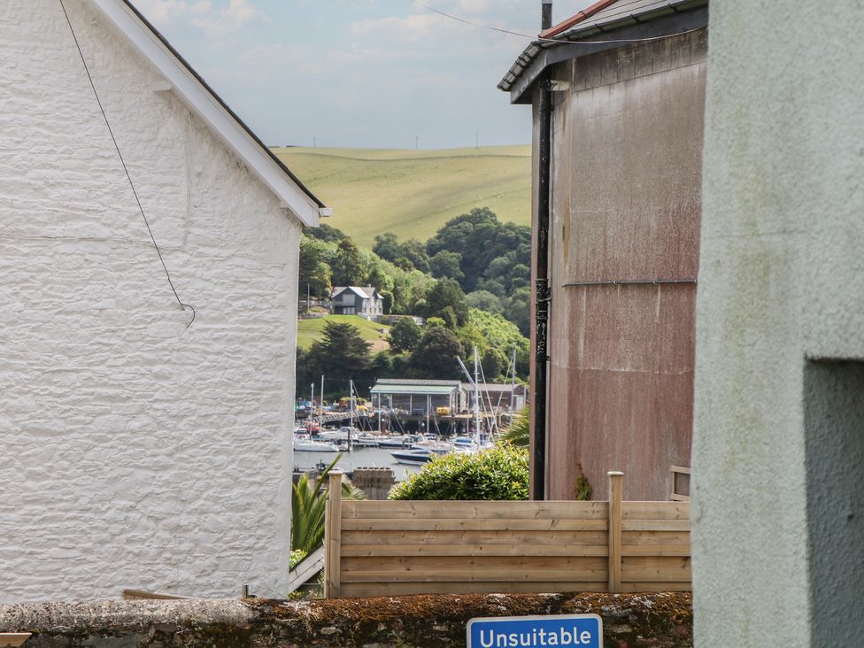 A view between houses showing boats near water at Tiller Cottage in Dartmouth