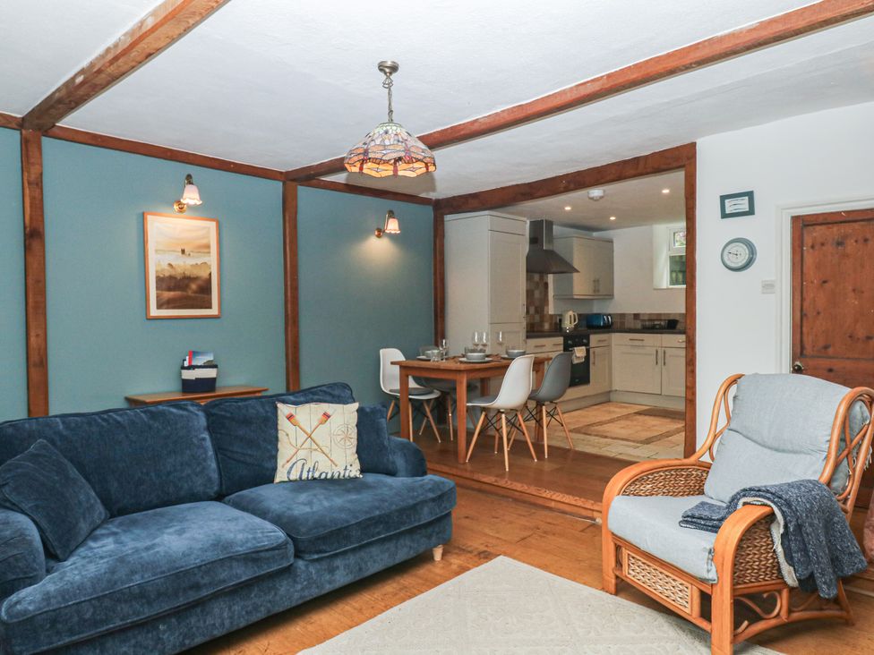 A living room with a sofa and dining area at Tiller Cottage in Dartmouth
