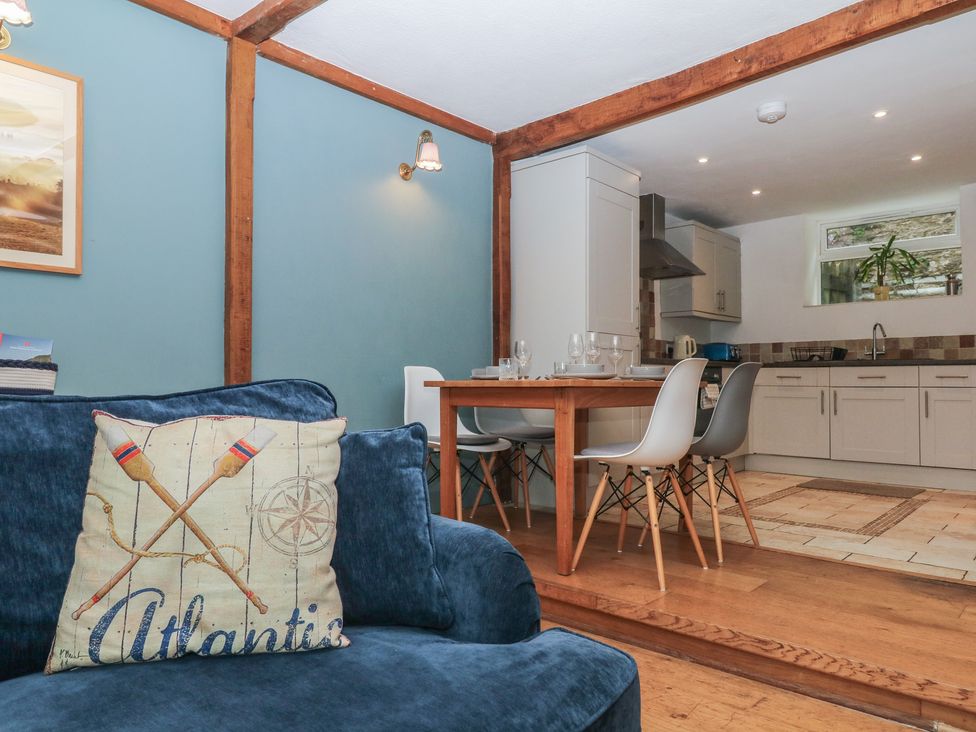 A dining room with a table and chairs adjacent to a kitchen at Tiller Cottage in Dartmouth