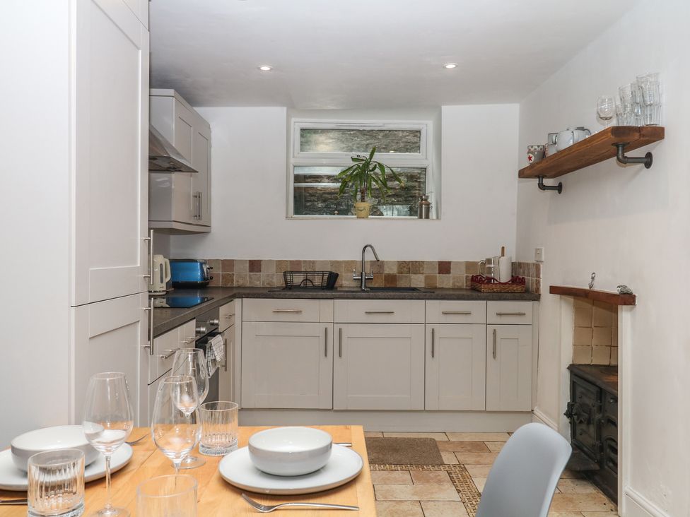 A kitchen with cabinets, stove, sink, and dining set at Tiller Cottage in Dartmouth