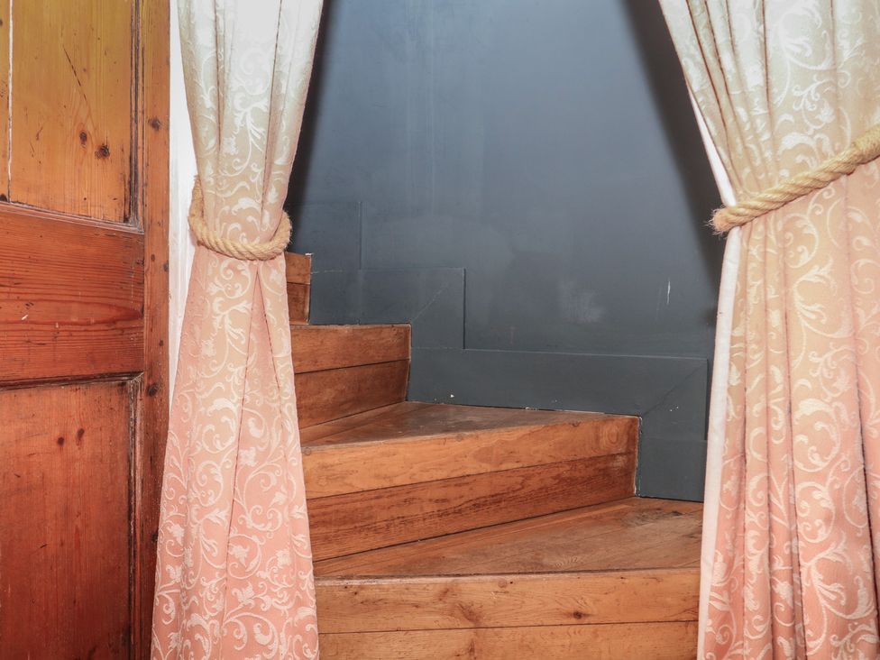 A staircase with wooden steps and curtains at Tiller Cottage in Dartmouth