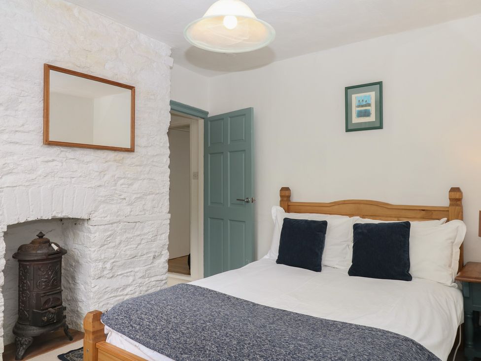 A bedroom with a bed and furniture at Tiller Cottage Dartmouth