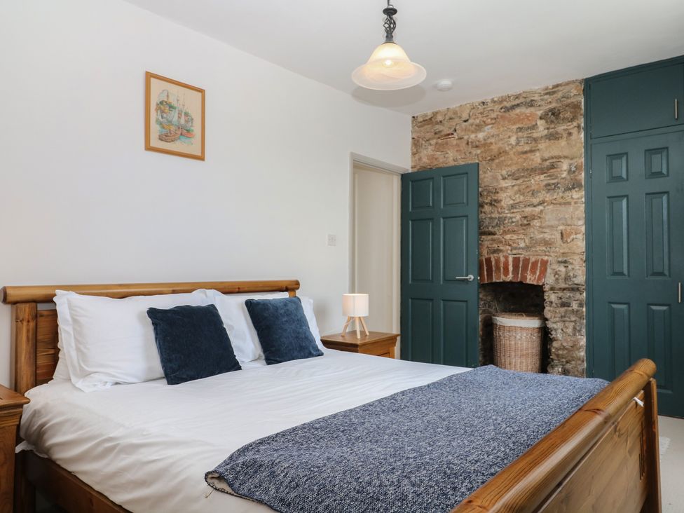 A bedroom with a bed and bedside table at Tiller Cottage in Dartmouth