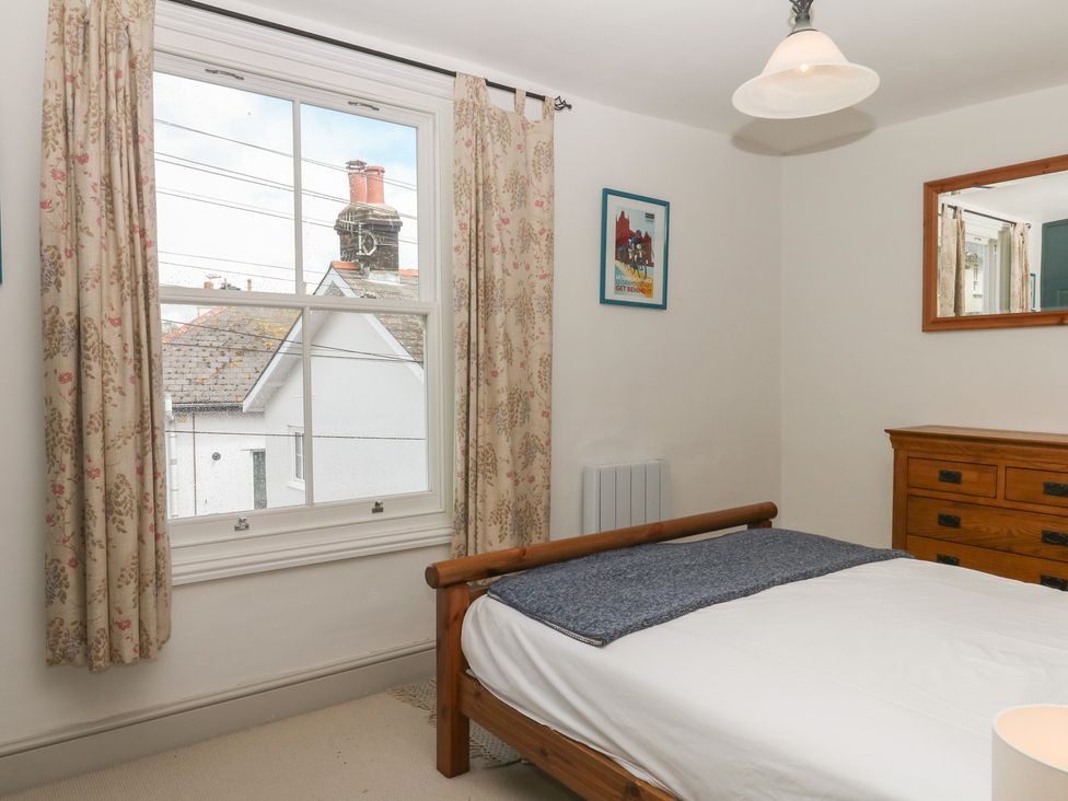 A bedroom with a bed and dresser at Tiller Cottage in Dartmouth
