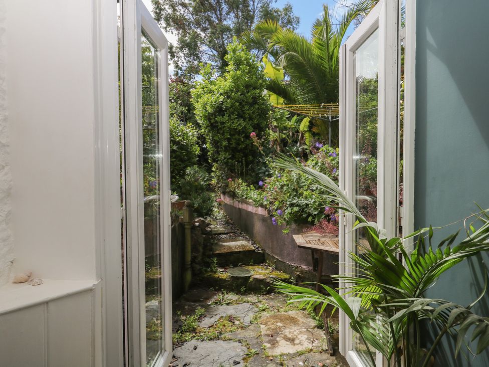 A view of a garden through open doors at Tiller Cottage in Dartmouth
