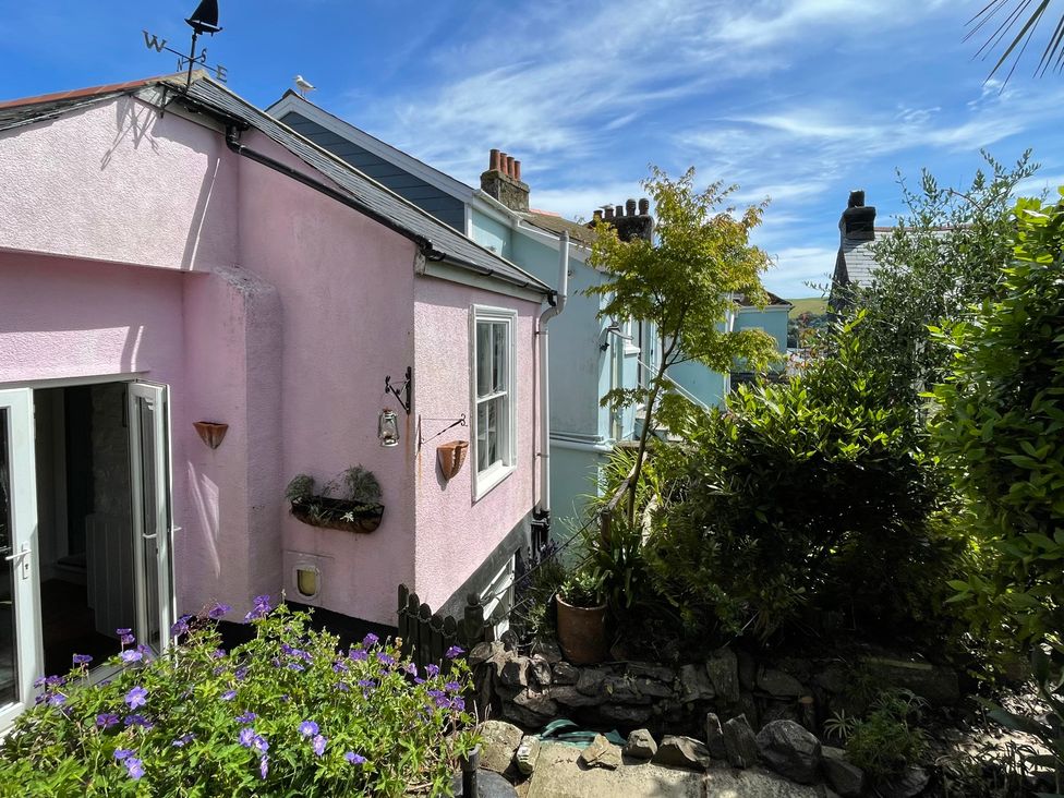 An outdoor view of a pink house with garden features at Tiller Cottage in Dartmouth