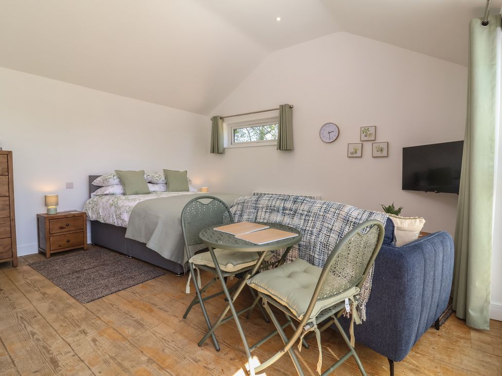 A bedroom with a bed, sofa, and dining table at Willow Barnstaple