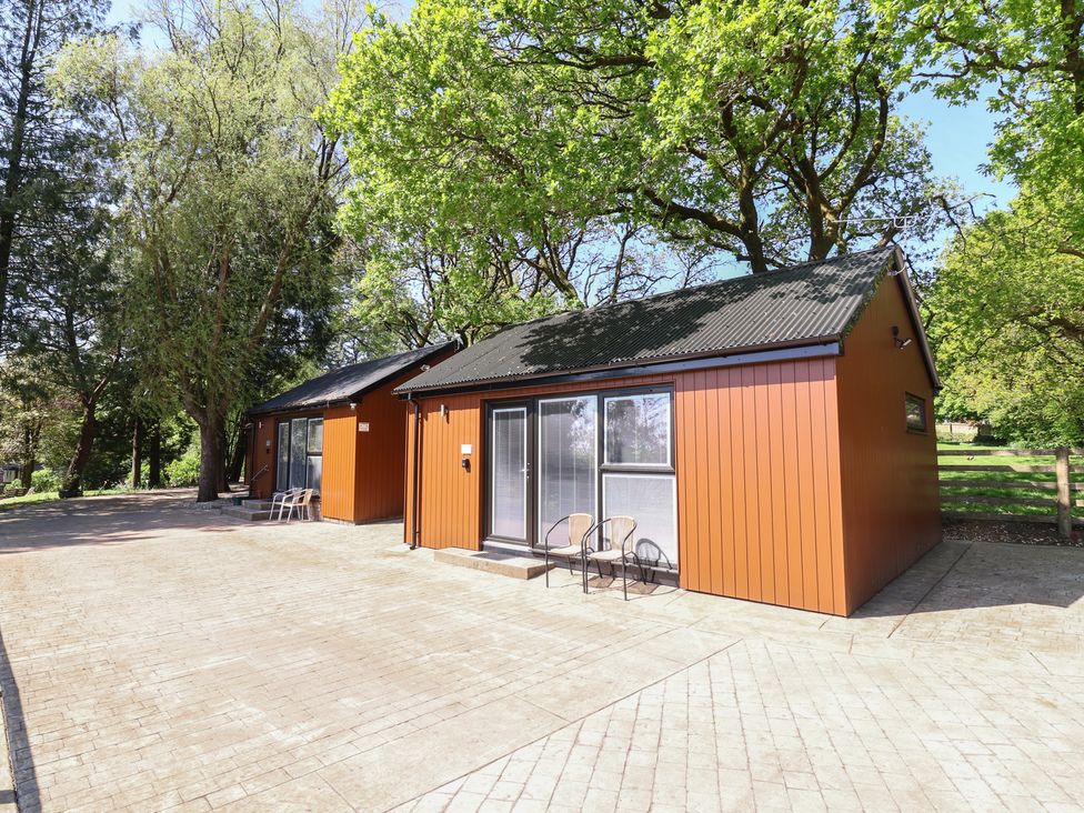 Two cabins with seating area and trees at Willow in Barnstaple