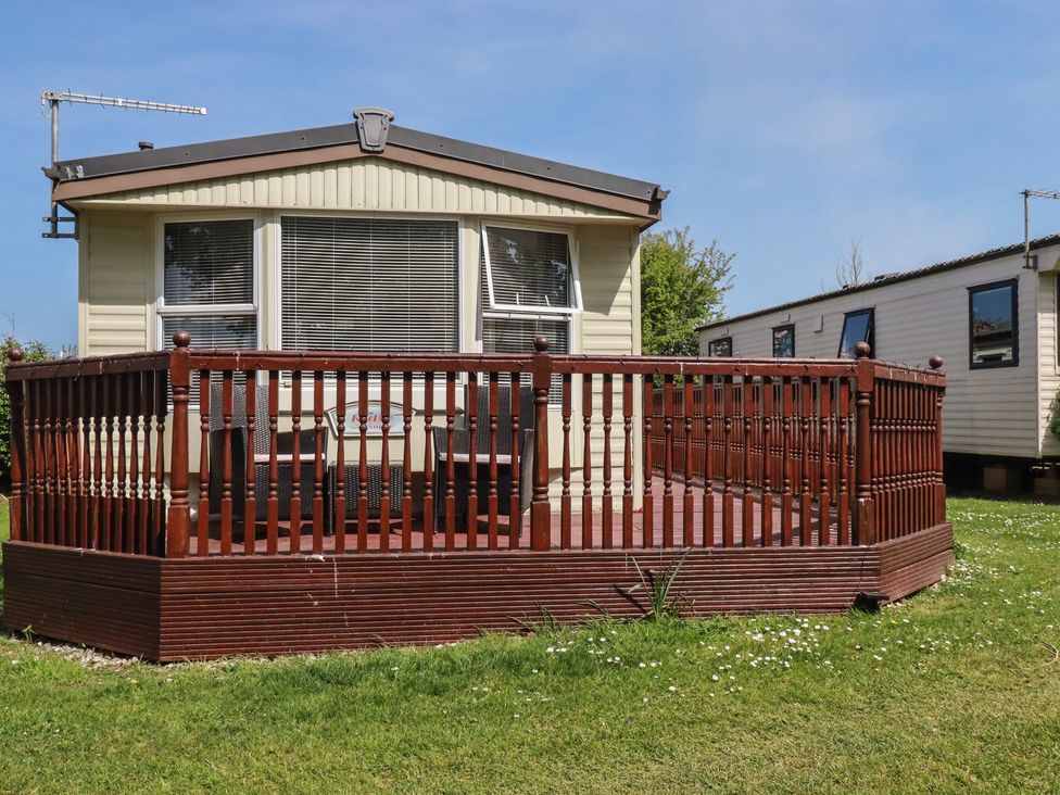 A mobile home with a deck and grass at Beech Lodge in Wadebridge