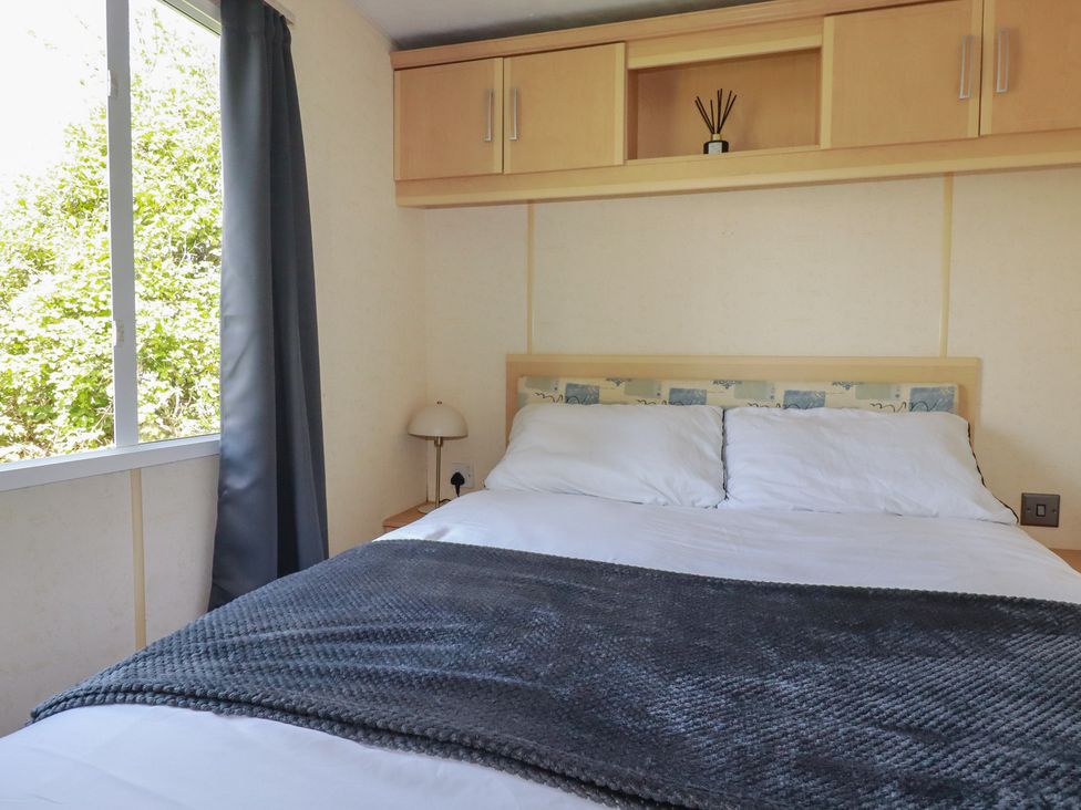 A bedroom with a bed and bedside lamp at Beech Lodge in Wadebridge
