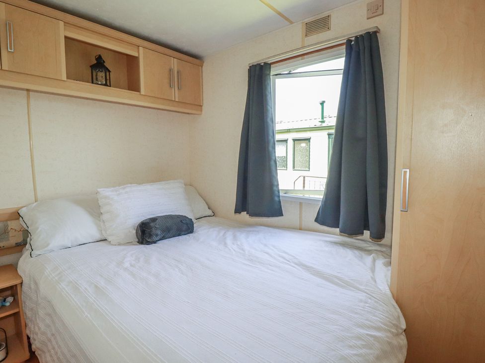 A bedroom with a bed and window at Beech Lodge in Wadebridge