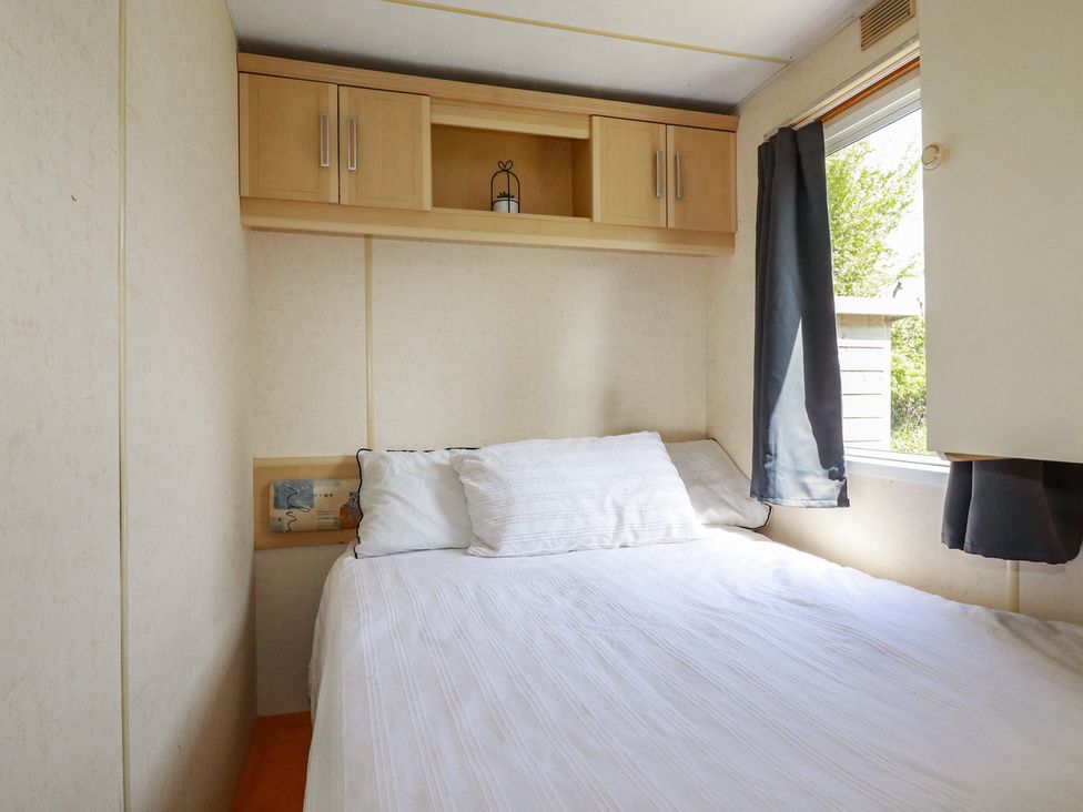 A bedroom with a bed and a window at Beech Lodge in Wadebridge