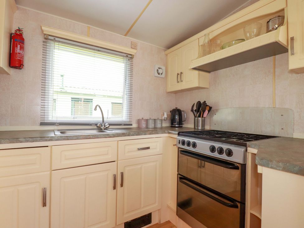 A kitchen with a stove and sink at Beech Lodge in Wadebridge