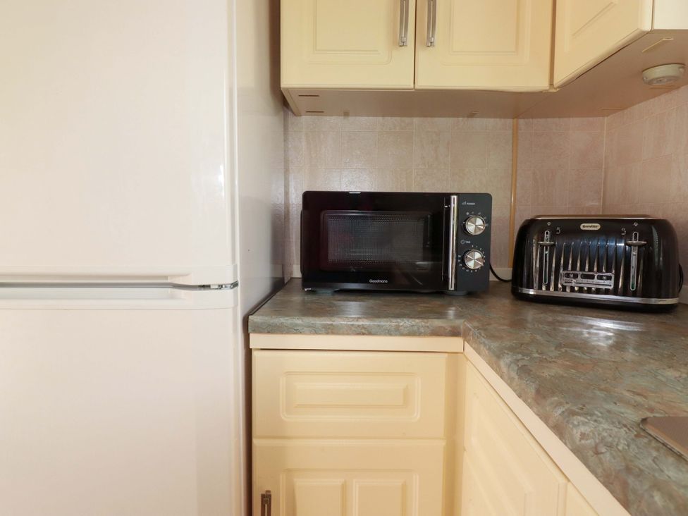 A kitchen with a refrigerator, microwave, and toaster at Beech Lodge in Wadebridge