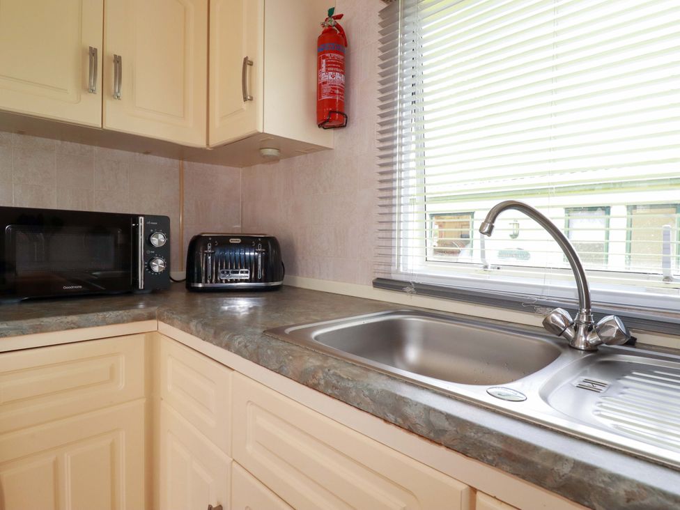 A kitchen with a microwave, toaster, and sink at Beech Lodge in Wadebridge