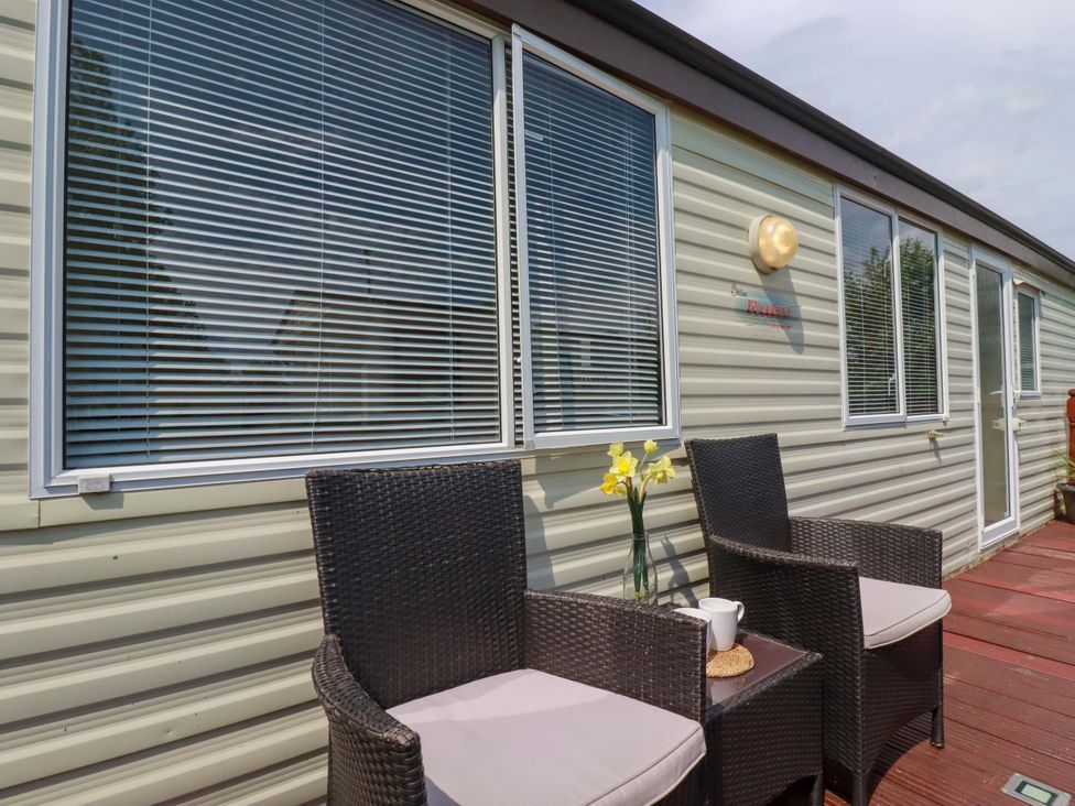 An outdoor seating area with chairs and a table at Beech Lodge in Wadebridge