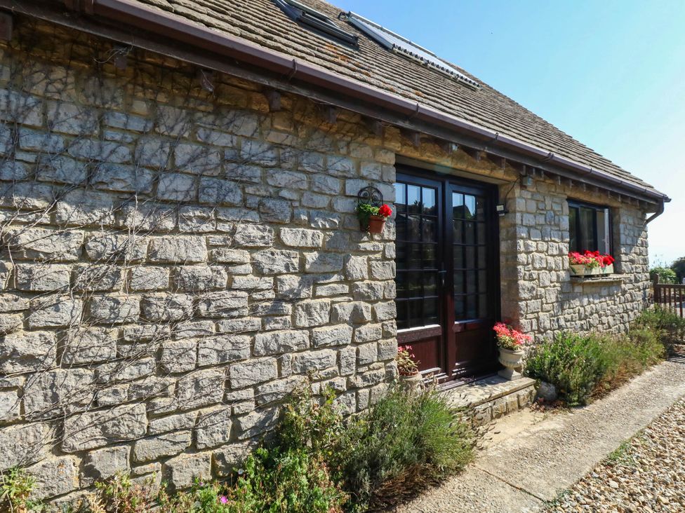 A stone wall with flowers and a pathway at Dunvant in Swanage