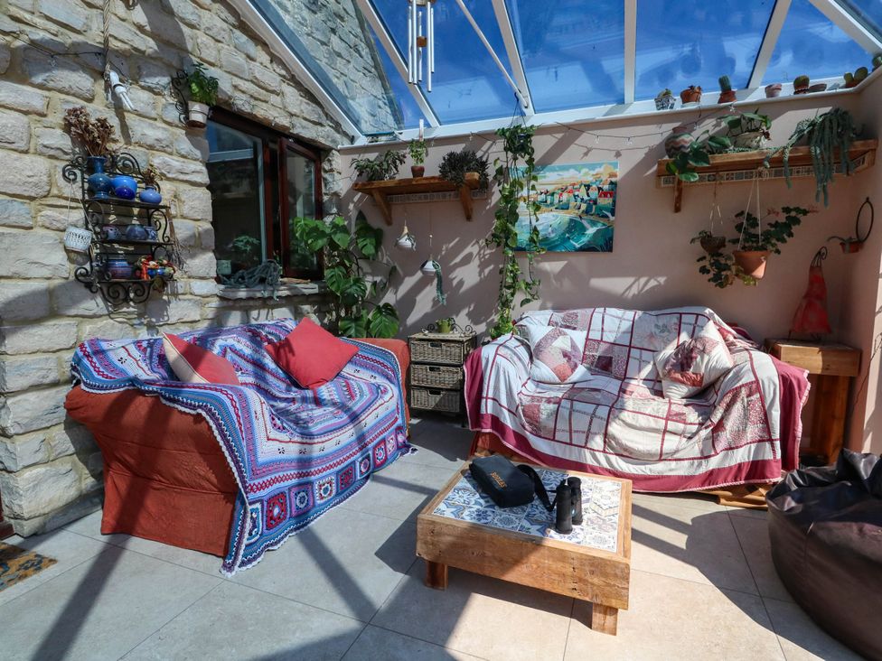 A conservatory with sofas and plants at Dunvant in Swanage