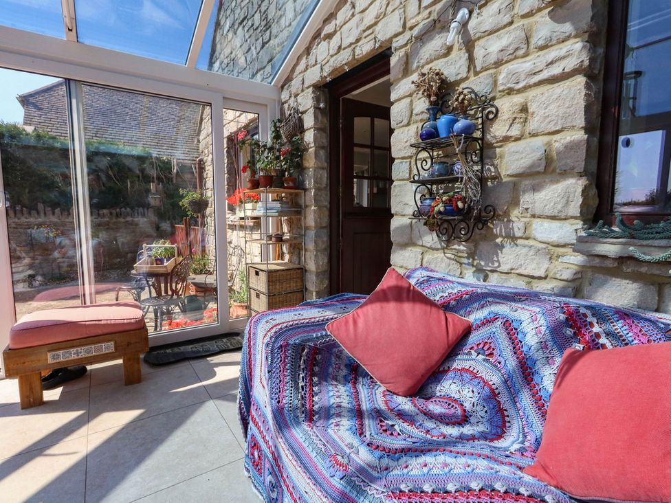 A conservatory with a sofa and plants at Dunvant in Swanage