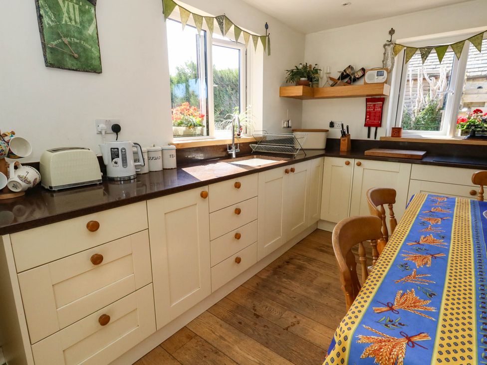 A kitchen with cabinets, sink, and a table at Dunvant in Swanage
