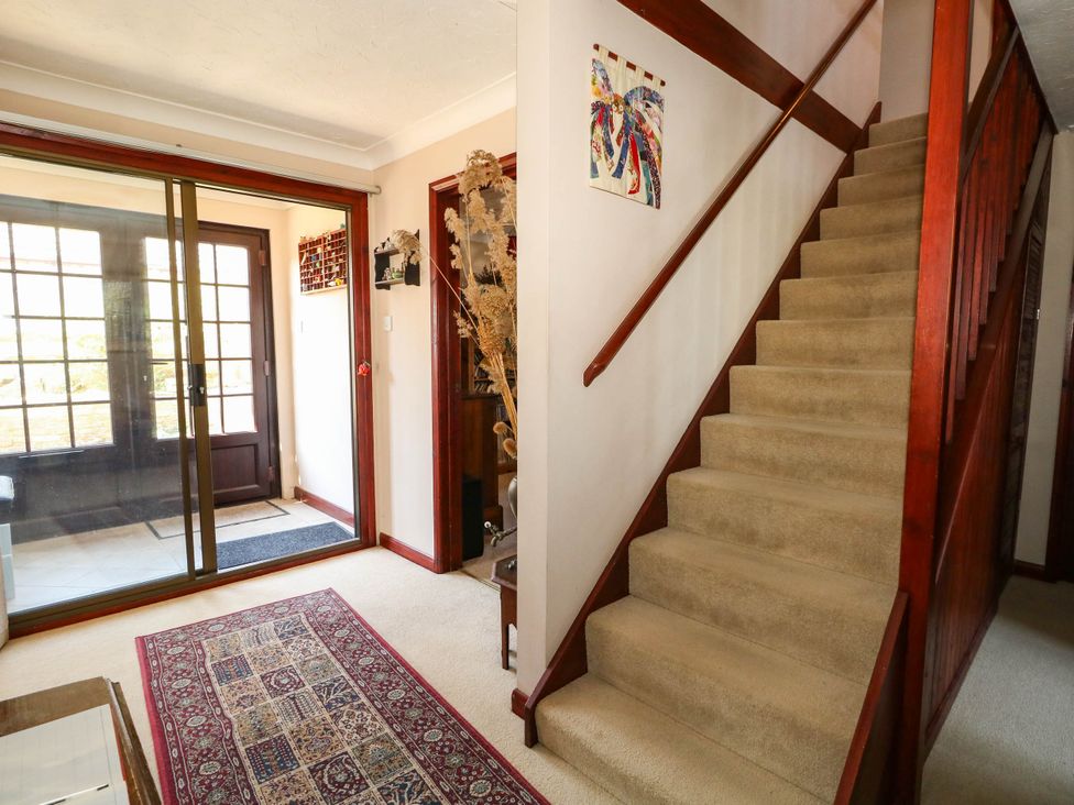 A hallway with a staircase and a front door at Dunvant in Swanage