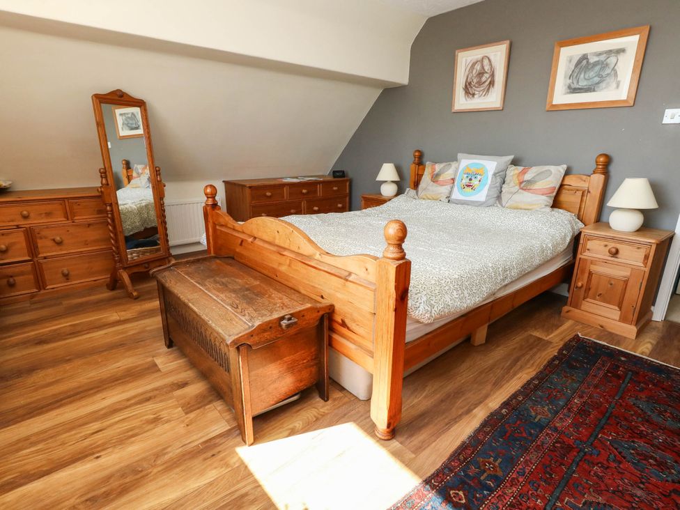A bedroom with a wooden bed and furniture at Dunvant in Swanage