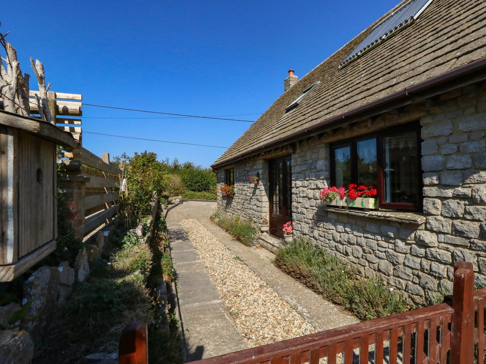 An outdoor view of a stone cottage with a pathway at Dunvant in Swanage