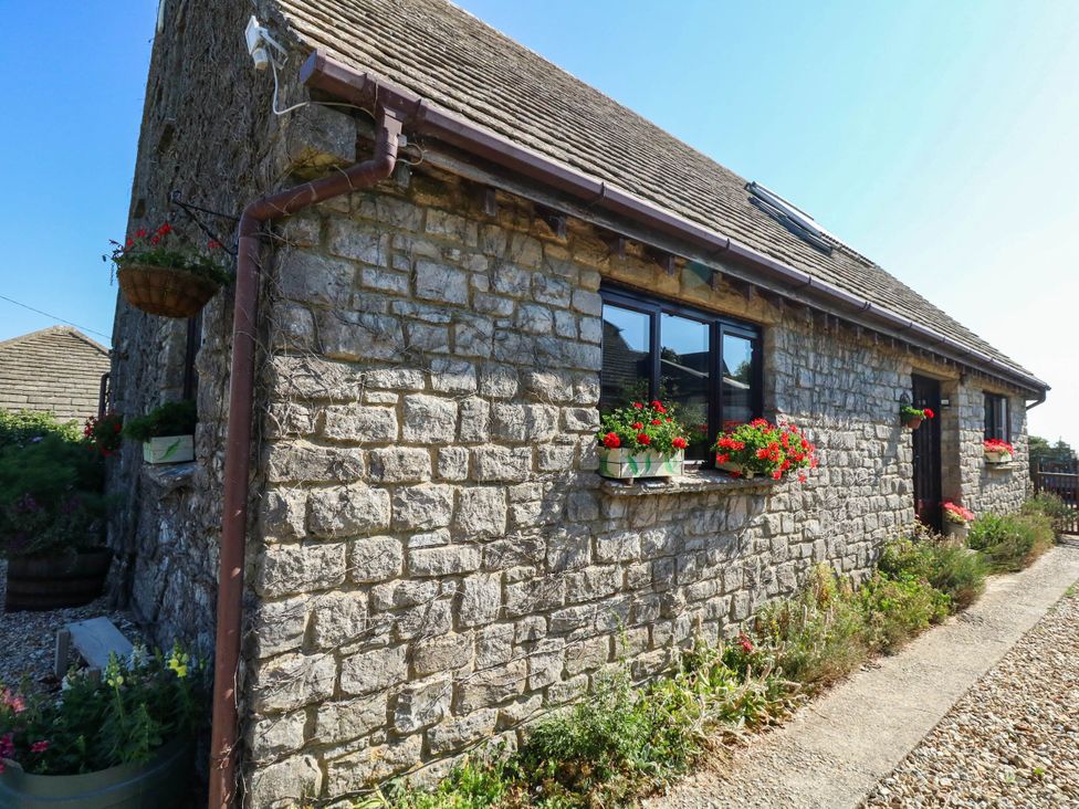 A stone cottage with flower boxes and a pathway at Dunvant in Swanage