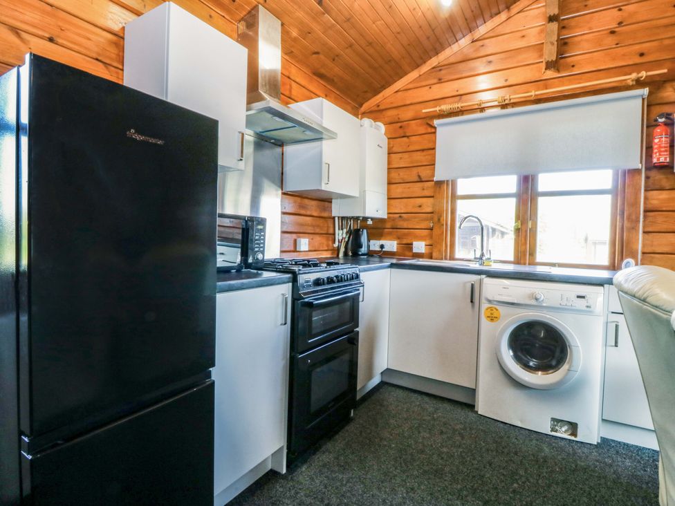 A kitchen with appliances including a fridge and stove at Lodge 7 - Bron Eifion in Criccieth