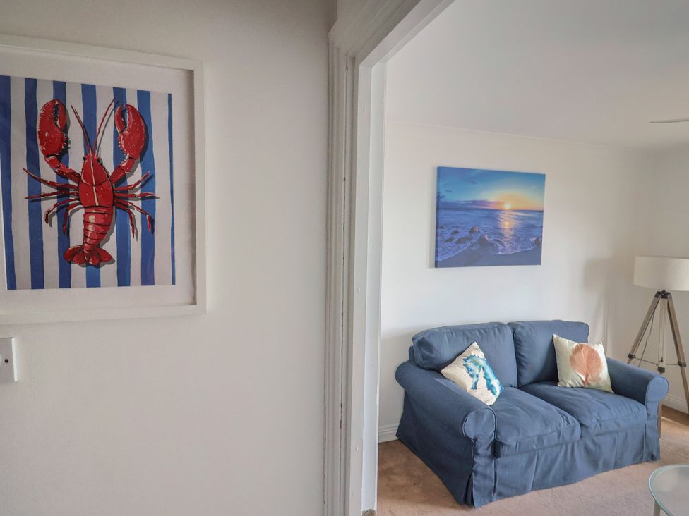 A living room featuring a sofa and framed artwork at 2 Lyme Mews Seaton