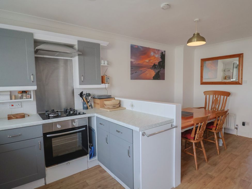 A kitchen with a stove and dining area at 2 Lyme Mews in Seaton
