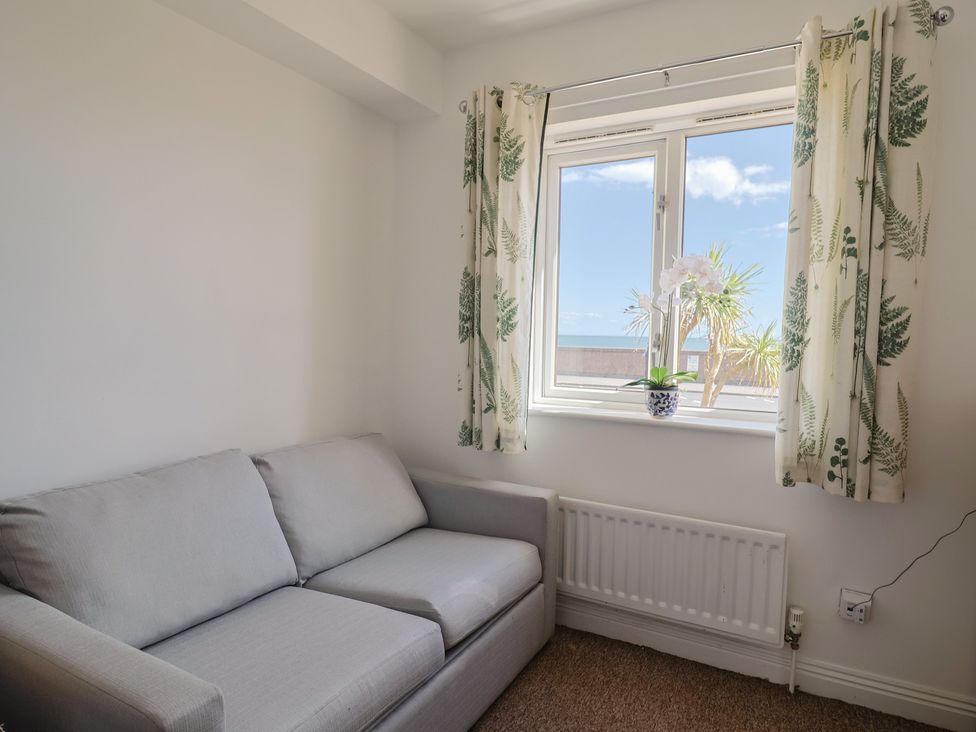 A snug room with a sofa and window at 2 Lyme Mews Seaton