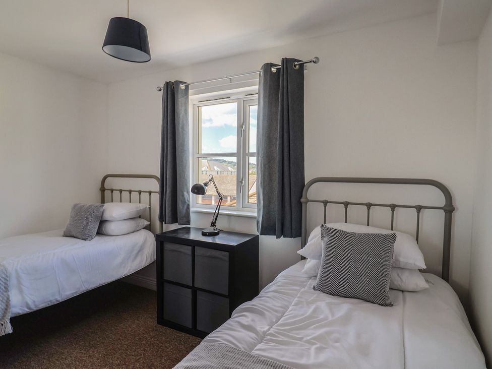 A bedroom with two beds and a window at 2 Lyme Mews Seaton