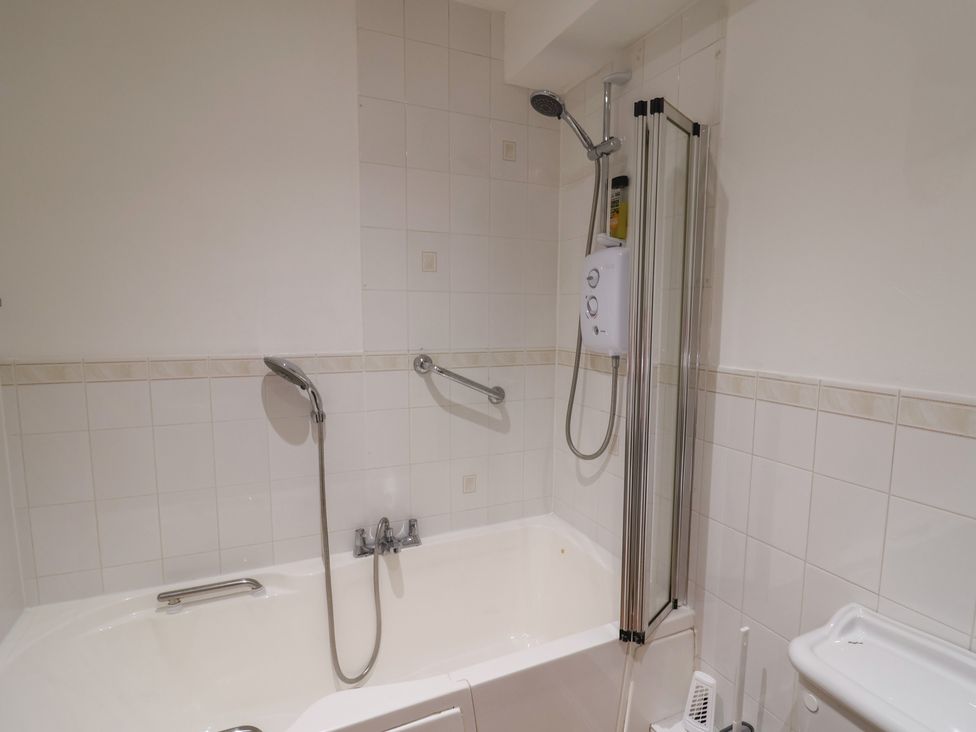 A bathroom with a bathtub and shower at 2 Lyme Mews Seaton