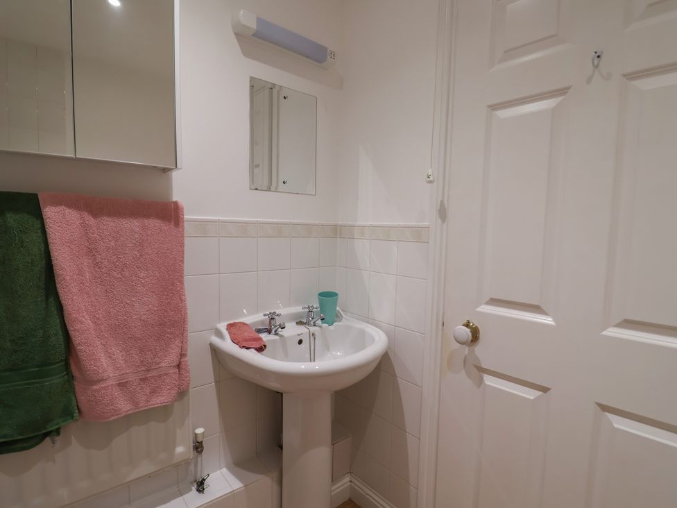 A bathroom with a wash basin and towels at 2 Lyme Mews Seaton
