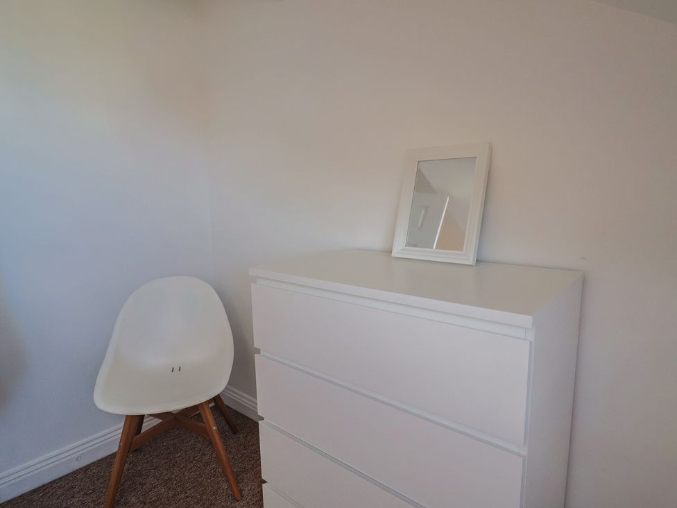 A bedroom with a dresser and a chair at 2 Lyme Mews in Seaton