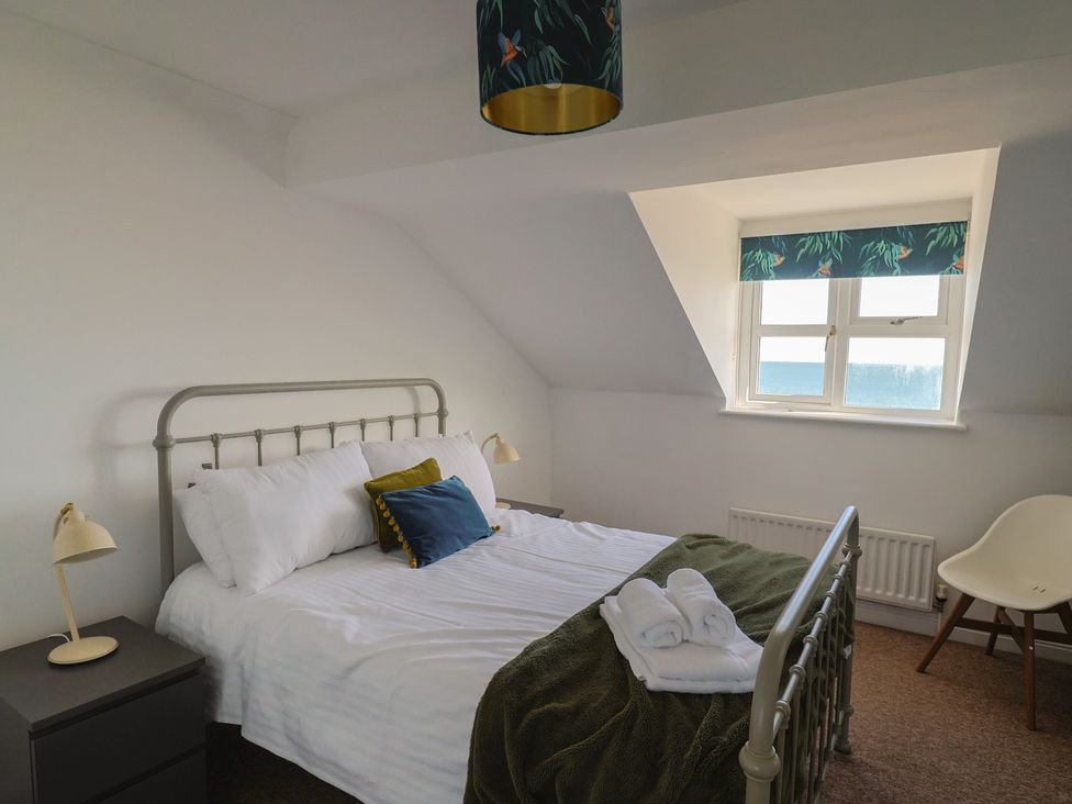 A bedroom with a bed and bedside lamp at 2 Lyme Mews in Seaton