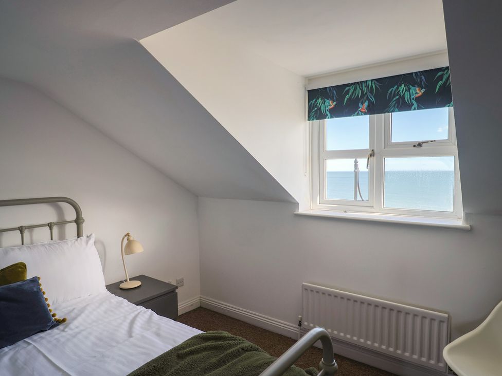 A bedroom with a bed and window overlooking the sea at 2 Lyme Mews in Seaton