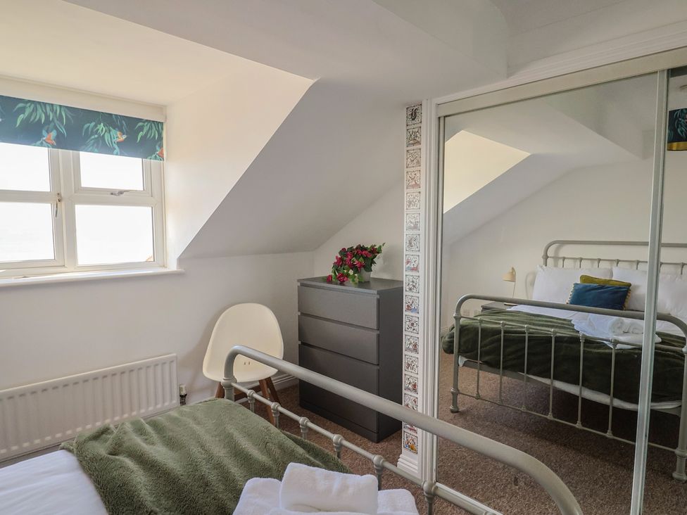 A bedroom with a bed, nightstand, and window at 2 Lyme Mews, Seaton