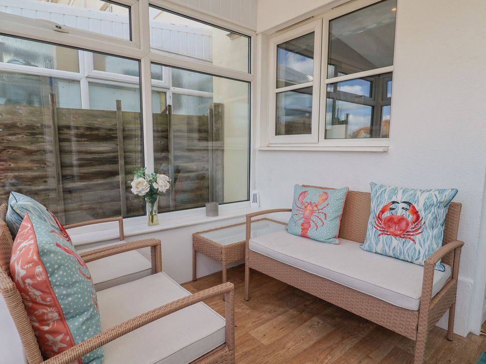 A conservatory with seating and decorative pillows at 2 Lyme Mews Seaton
