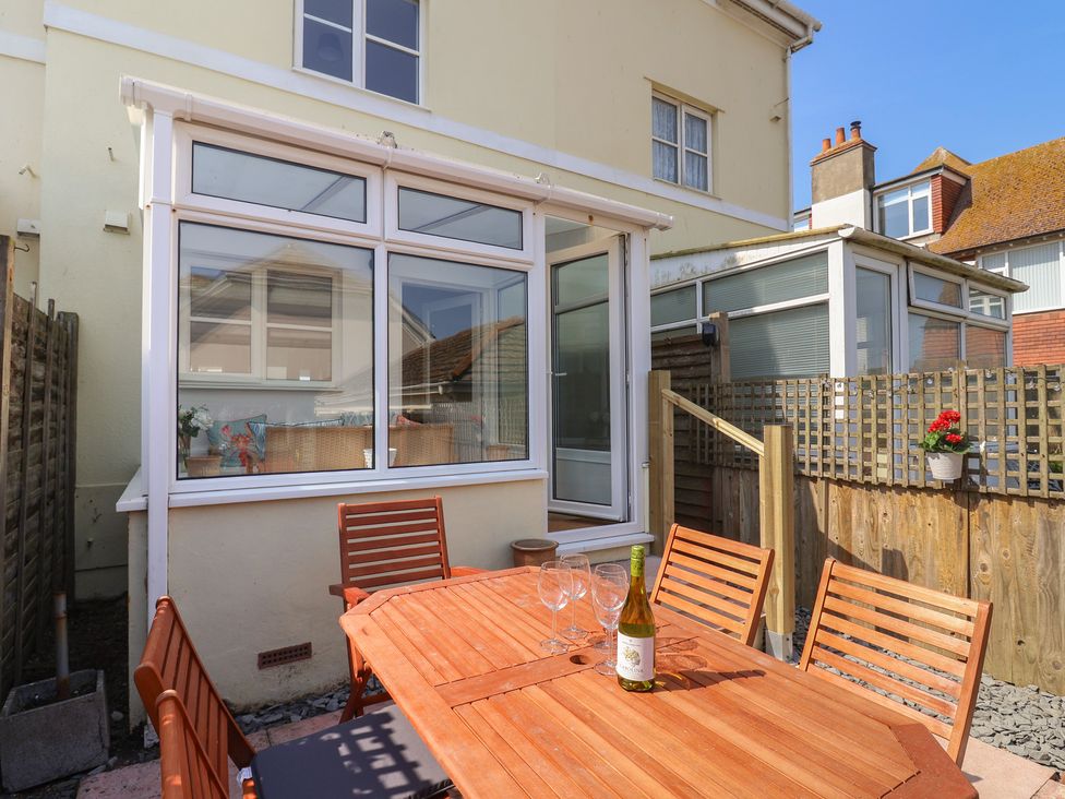 A garden with a wooden table and chairs at 2 Lyme Mews Seaton