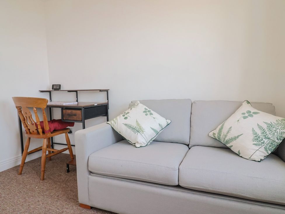 A living room with a sofa and desk at 2 Lyme Mews Seaton