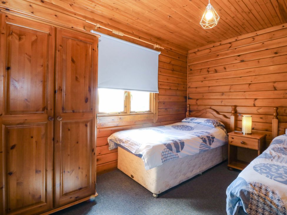 A bedroom with two beds and a wardrobe at Lodge 9 - Sleep 4 - Double and Twin in Criccieth