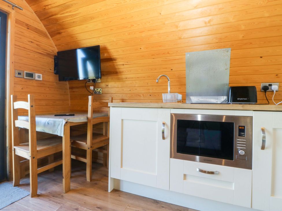 A kitchen with a table and chairs at Bron Eifion Pod 3 in Criccieth