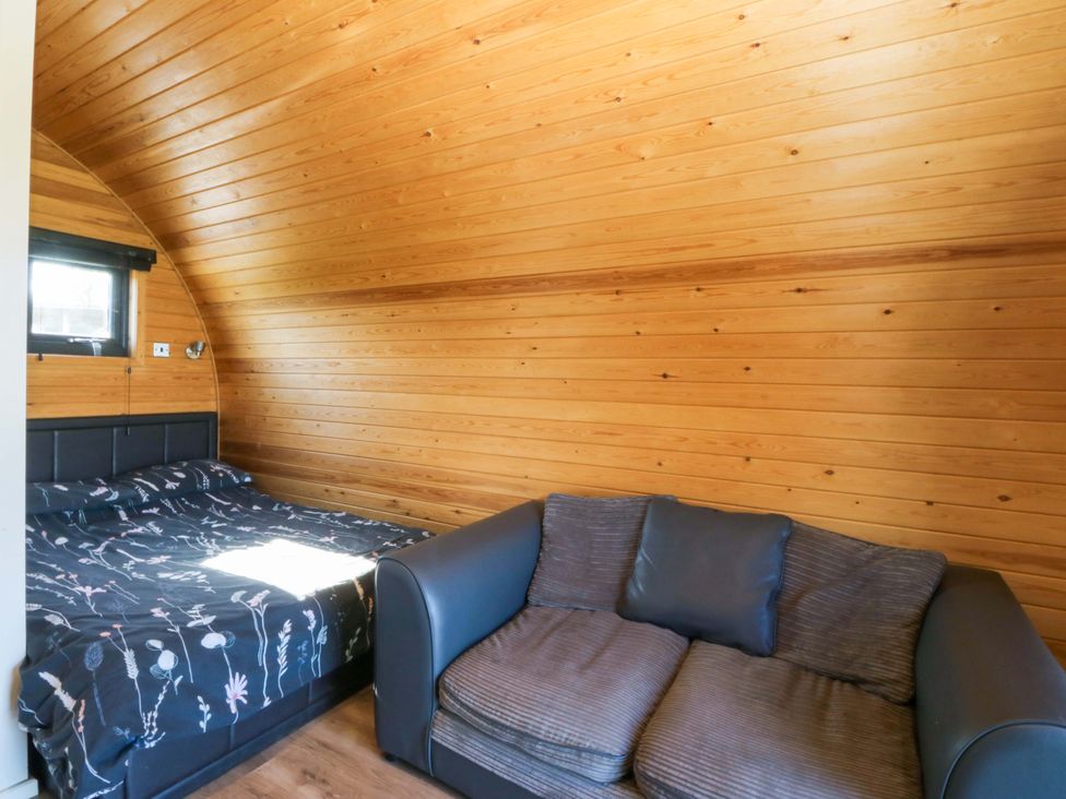 A bedroom with a bed and sofa at Bron Eifion Pod 3 Criccieth