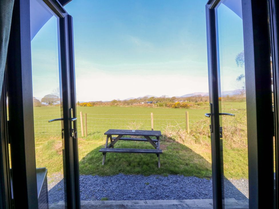 A view of a picnic bench and a grassy field at Bron Eifion Pod 3 in Criccieth
