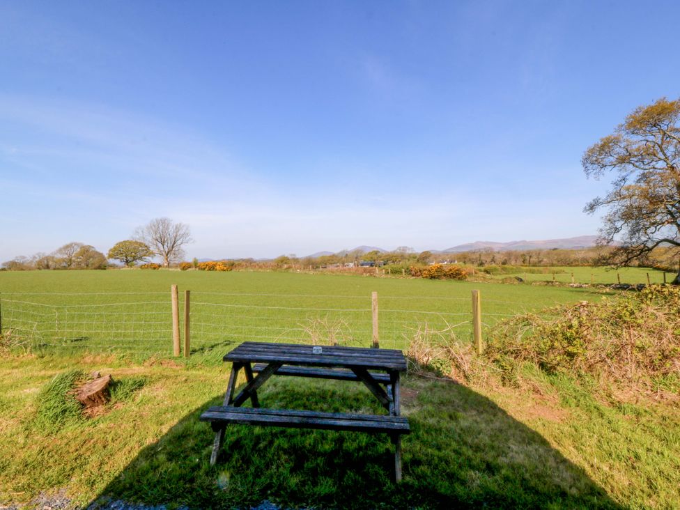 An outdoor area with a table and a view of fields and mountains at Bron Eifion Pod 4 Criccieth