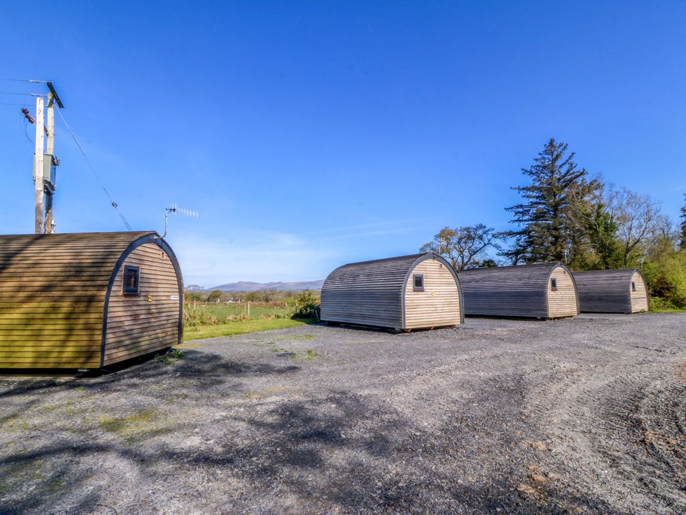 A group of wooden cabins in a gravel area at Bron Eifion Pod 5 Criccieth