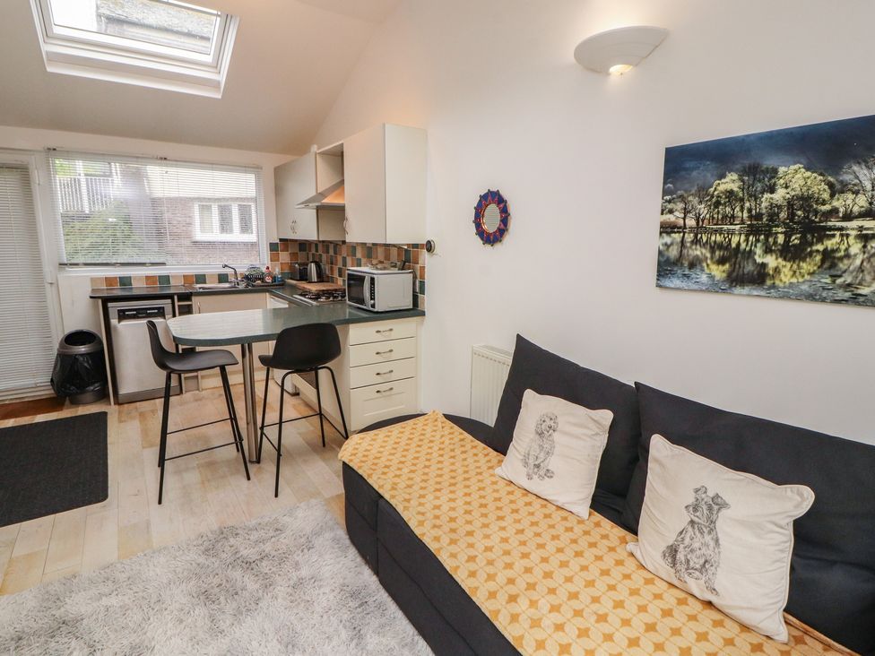A kitchen area with a couch and bar stools at Juniper Hayloft in Ambleside