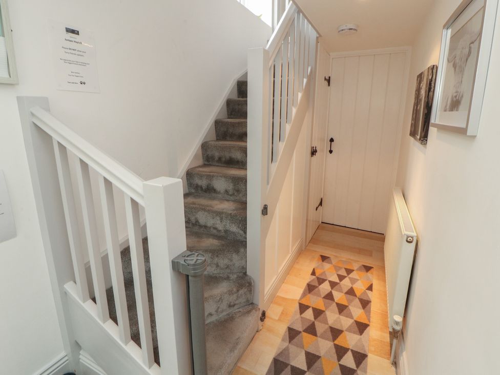 A hallway with stairs leading up and a door at Juniper Hayloft in Ambleside